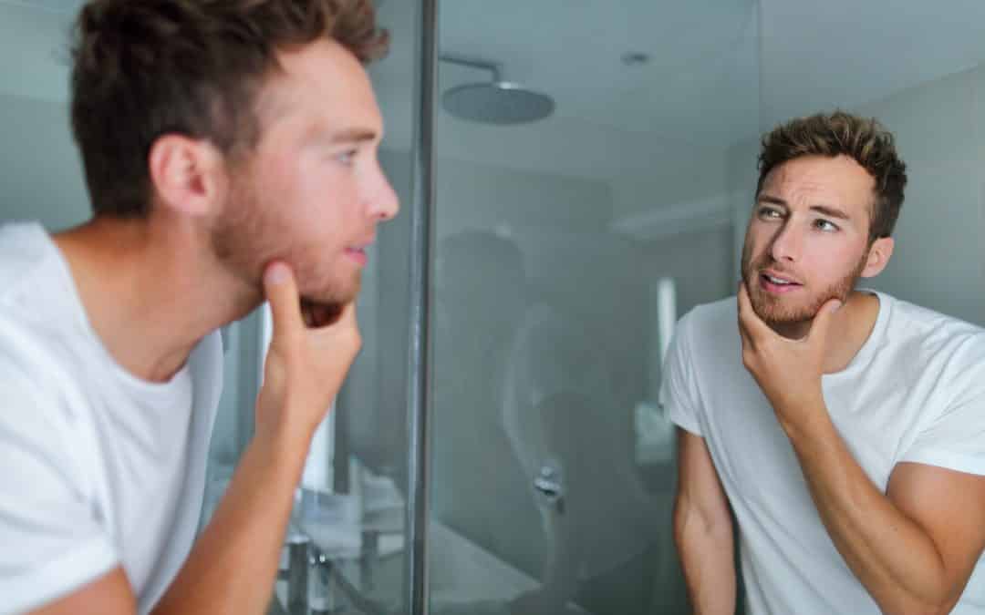 Man with Acne Looking at the Mirror