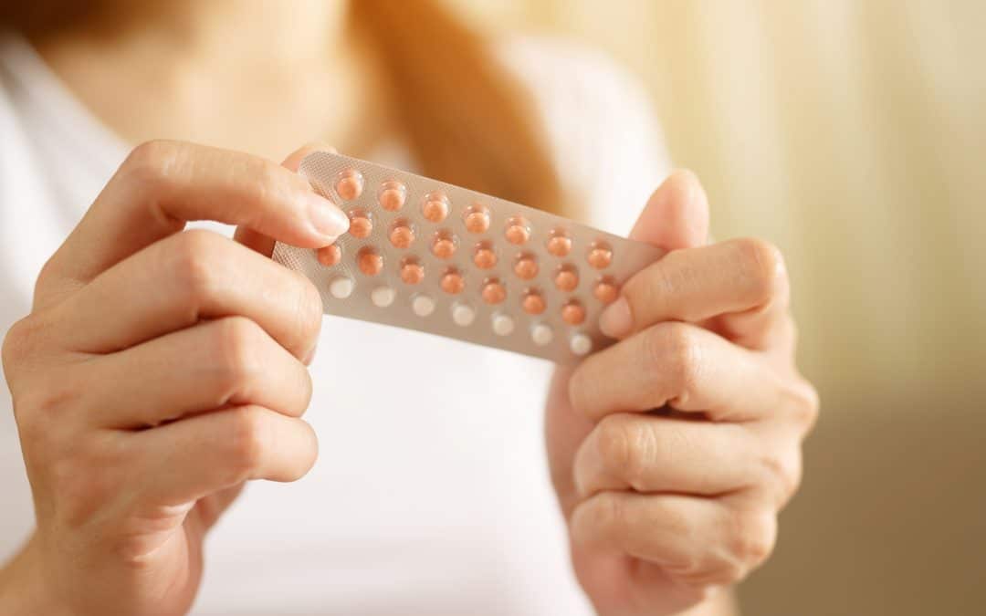 Woman holding birth control pills